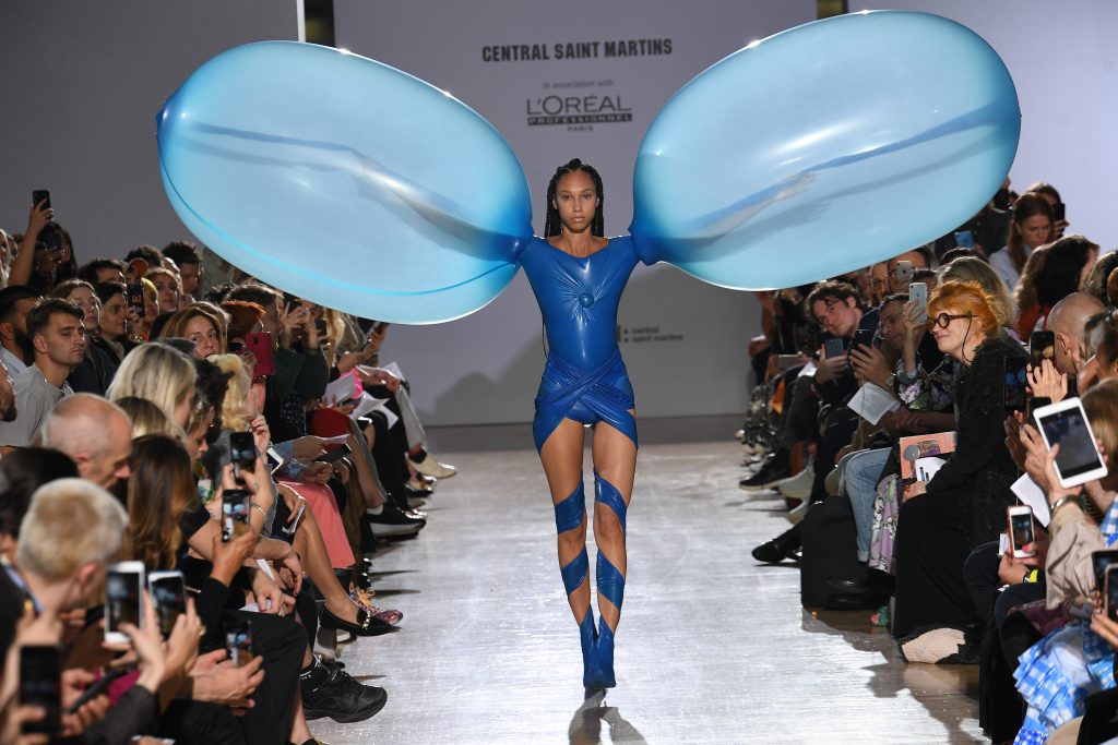 Woman wearing blue latex bubble dress with arms outstretched