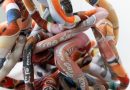 Close up of a fabric sculpture, with thick spaghetti-like tubes made of orange, white and blue patterned material
